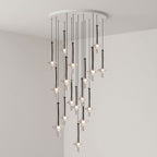 Black-stemmed Clérachic pendants spread wide at varied heights from a round canopy, lit in the corner of a grey room.