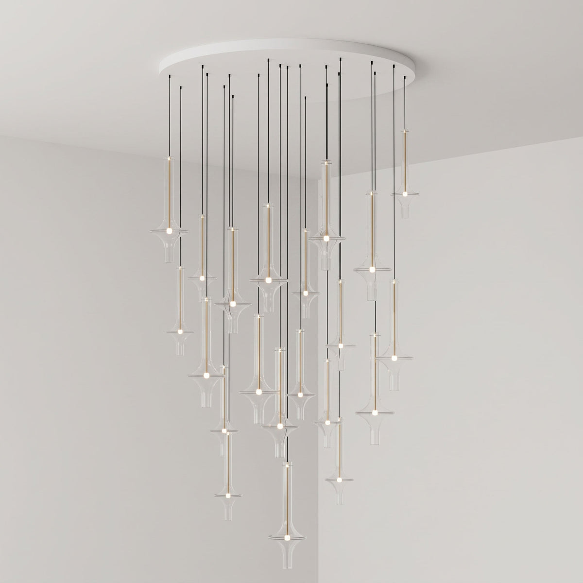 Gold-stemmed Clérachic pendants cascade unevenly from a round canopy, lit in clear glass in the corner of a grey room.