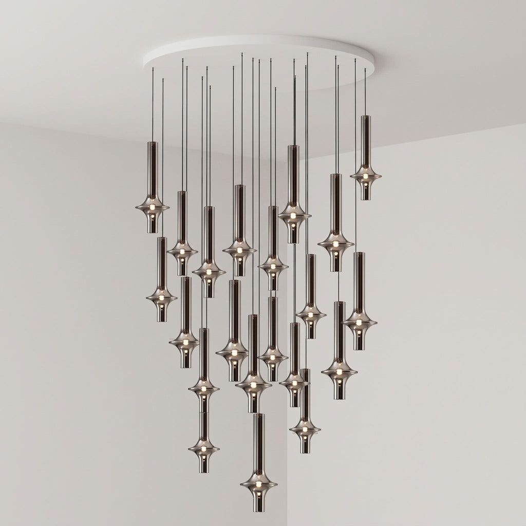A dense cluster of black-stemmed Clérachic pendants drops from a round canopy, lit closely together in a grey corner room.