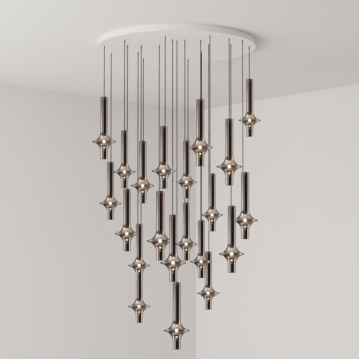 A dense cluster of black-stemmed Clérachic pendants drops from a round canopy, lit closely together in a grey corner room.