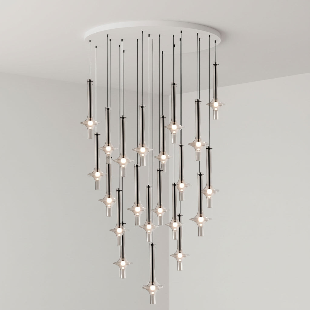 Black-stemmed Clérachic pendants drop in tight tiers from a round canopy, lit in clear glass in a grey corner room.