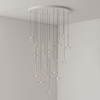 Gold-stemmed Clérachic pendants in clear glass cascade from a round canopy, lit in the corner of a plain grey room.
