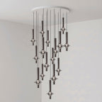 Black-stemmed Clérachic pendants hang unlit in a dense cluster from a round canopy, in the corner of a plain grey room.