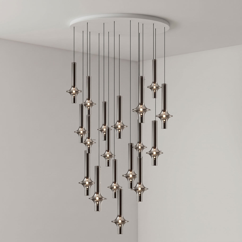 Black-stemmed Clérachic pendants cascade from a round canopy in a broad spread, lit in the corner of a grey room.