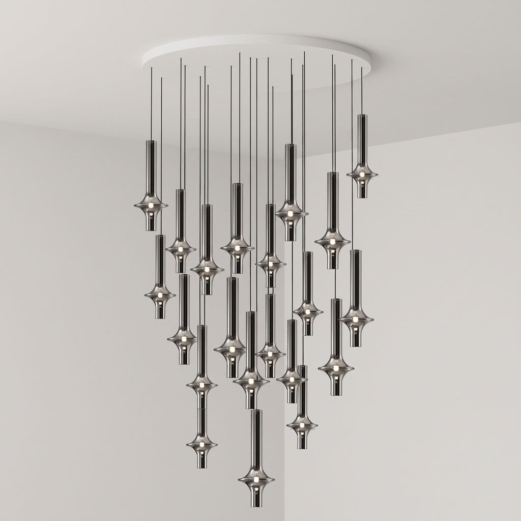 A dense cluster of lit black-stemmed Clérachic pendants drops from a round canopy in the corner of a grey room.