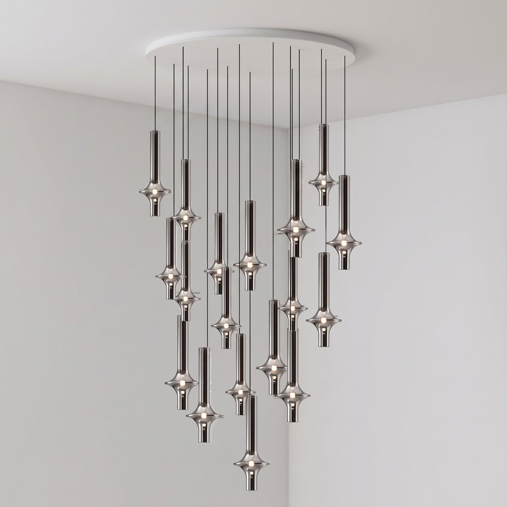 A sparser group of lit black-stemmed Clérachic pendants drops from a round canopy in the corner of a plain grey room.