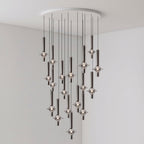 A sparser group of lit black-stemmed Clérachic pendants drops from a round canopy in the corner of a plain grey room.