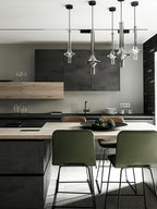 A cluster of Clérachic pendants in mixed finishes lights a kitchen island with dark cabinetry and green bar stools.