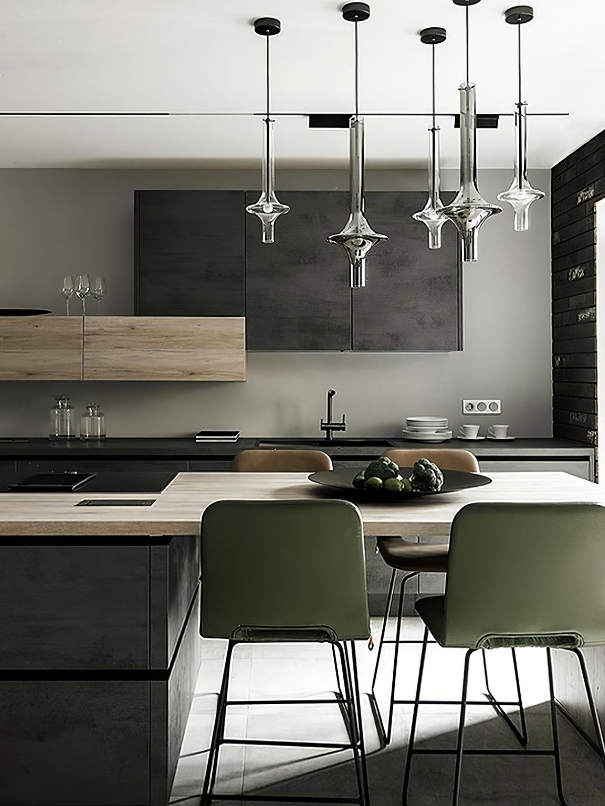 A cluster of Clérachic pendants in mixed finishes lights a kitchen island with dark cabinetry and green bar stools.
