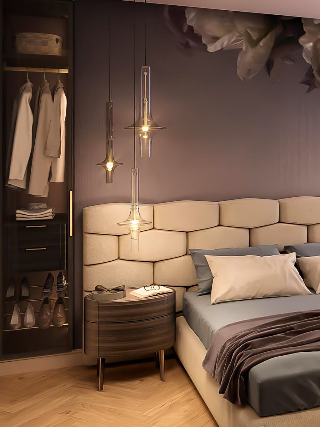 A single lit gold-stemmed Clérachic pendant hangs beside a bed, with hanging clothes visible in the dressing area behind it.