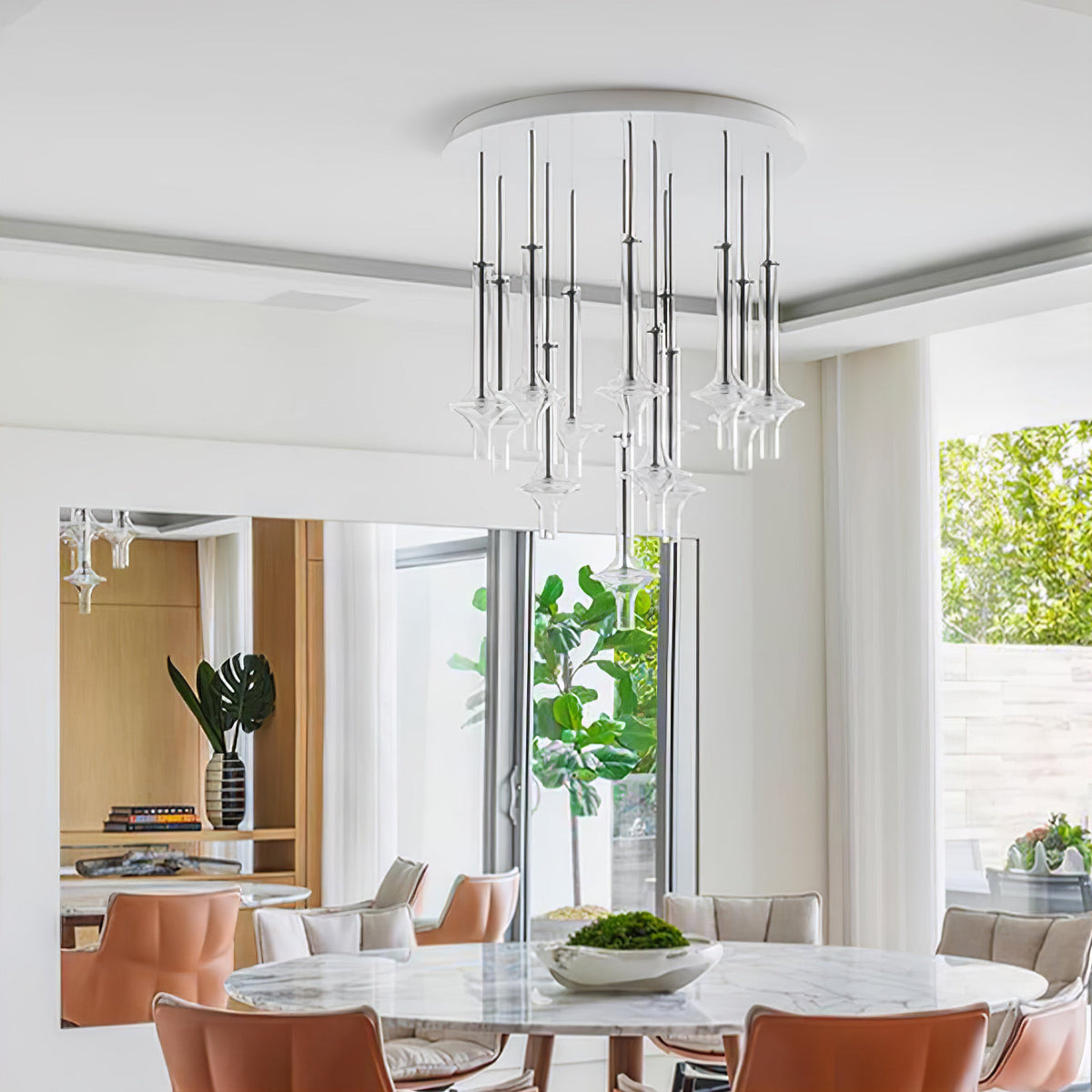 A cluster of Clérachic pendants in clear and nickel-toned glass hangs from a round ceiling plate above a dining table with tan chairs.
