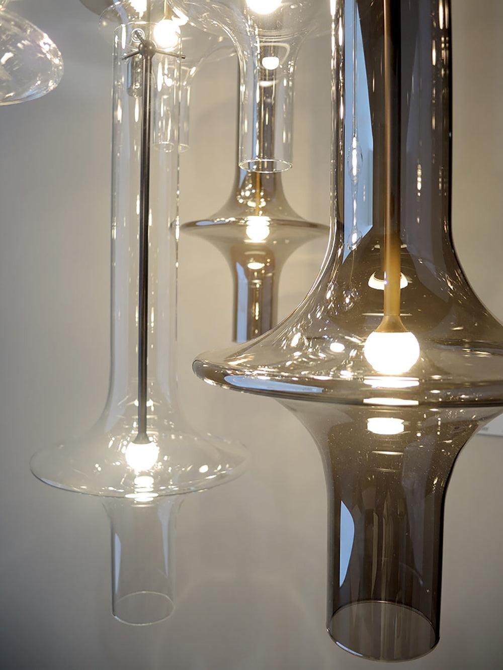 A close view of several lit Clérachic pendant heads shows their tapered clear and smoky glass side by side.
