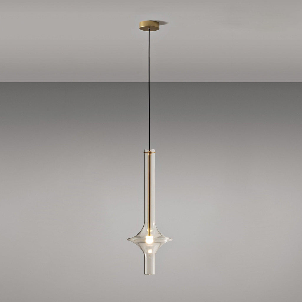 A single gold-stemmed Clérachic pendant with a matching gold ceiling canopy hangs against a plain grey backdrop.
