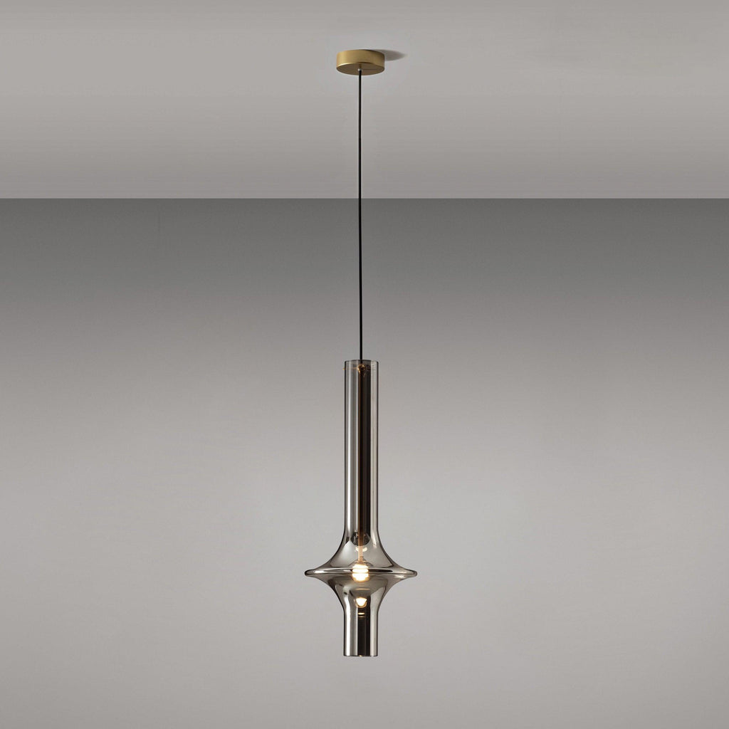 A single gold-stemmed Clérachic pendant in smoky grey glass hangs unlit against a plain grey backdrop, its gold canopy visible above.