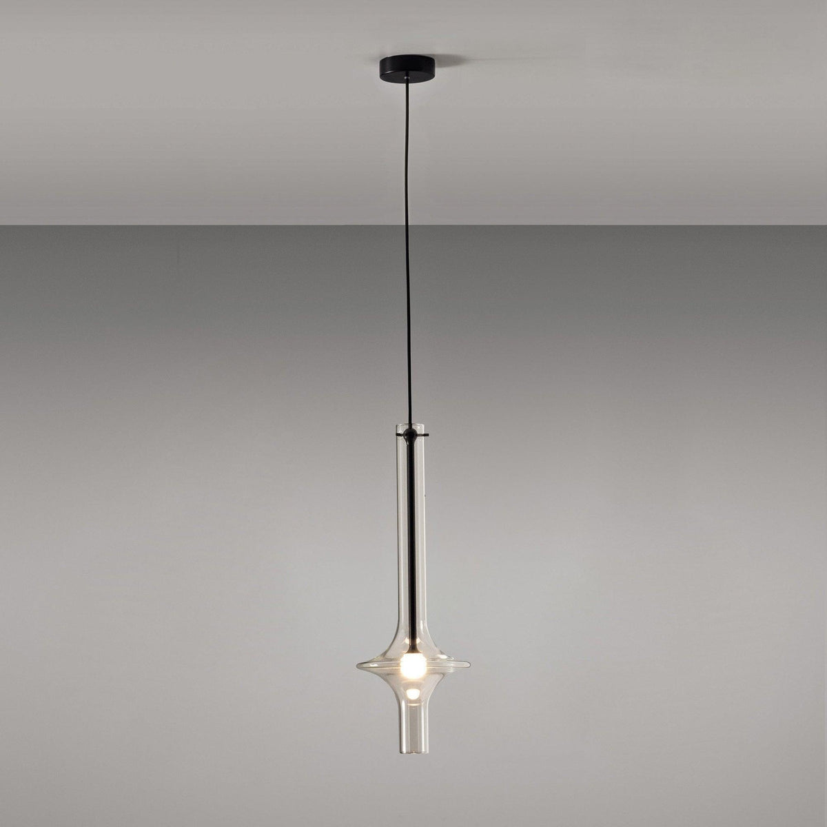 A single black-stemmed Clérachic pendant with a black ceiling canopy hangs unlit against a plain grey backdrop.
