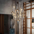 Gold and black-stemmed Clérachic pendants glow together in a stone-walled loft, beside a carved stone sculpture and a timber lattice door.
