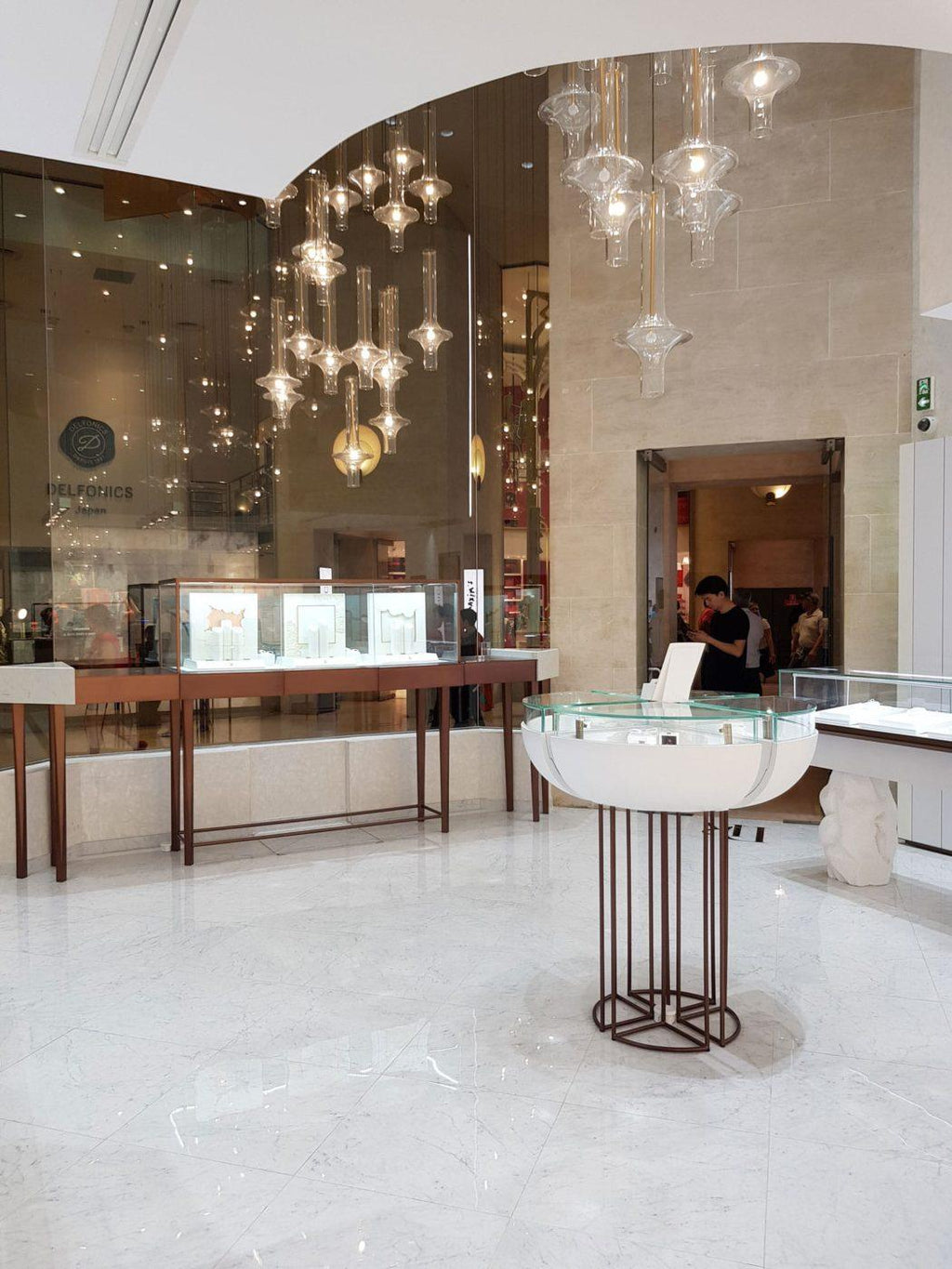 Several lit Clérachic pendants hang over glass display counters in a marble-floored boutique interior.