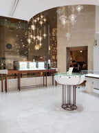 Several lit Clérachic pendants hang over glass display counters in a marble-floored boutique interior.