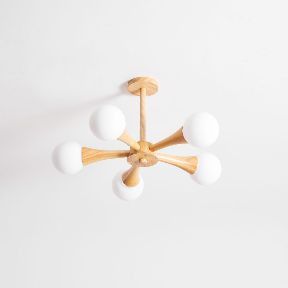 Side-angled view on a soft grey background, this Clérachic chandelier's ceiling mount sits to one side with its arms fanning right.