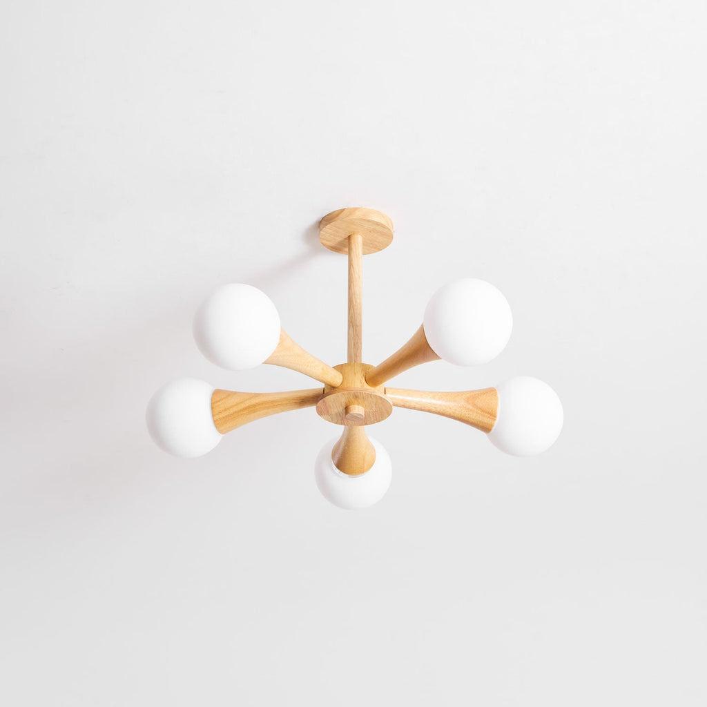 Side-angled view on a plain white background, this Clérachic chandelier's pale wood arms and opal globes are shown unlit.