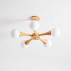 Viewed from slightly below on a plain white background, this Clérachic chandelier's ceiling mount and pale wood arms are shown unlit.