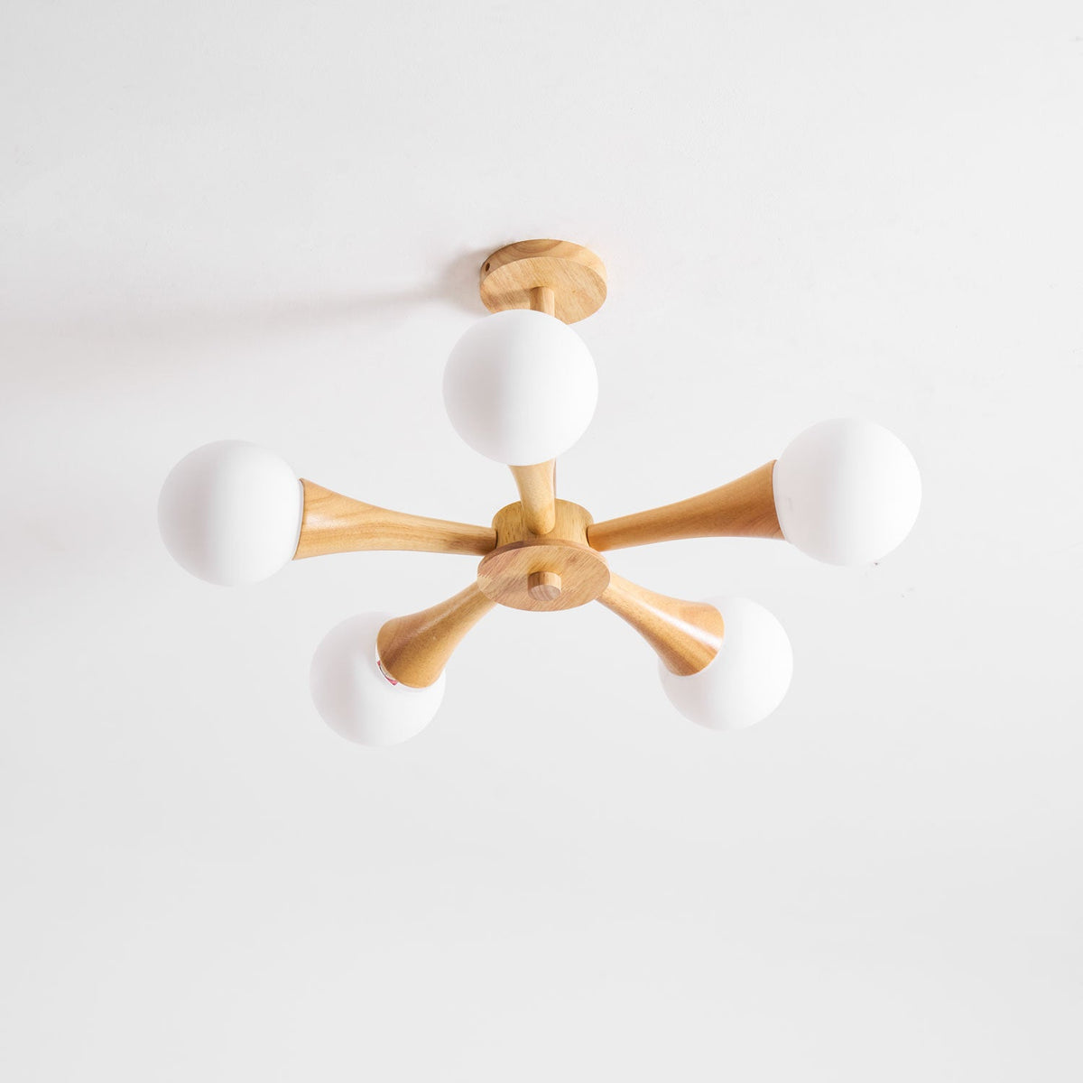Viewed from slightly below on a plain white background, this Clérachic chandelier's ceiling mount and pale wood arms are shown unlit.