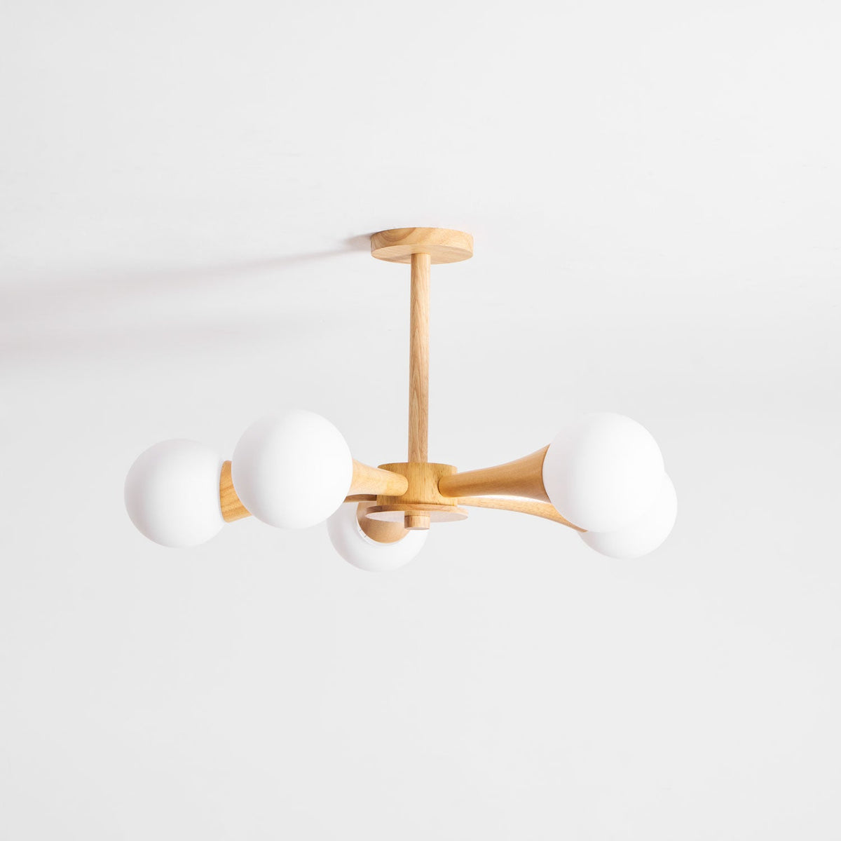 Side view on a plain white background, this Clérachic chandelier's arms extend left and right with an opal globe at each end.