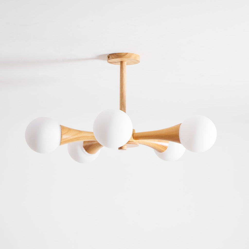 Rotated to a diagonal angle, this Clérachic chandelier's pale wood arms and opal glass globes sit unlit on a plain white background.