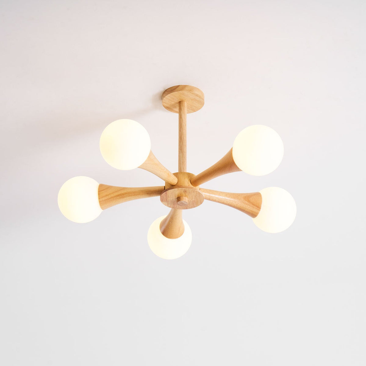 Photographed front-on against a plain white background, this Clérachic chandelier's five opal globes sit evenly around the pale wood centre.
