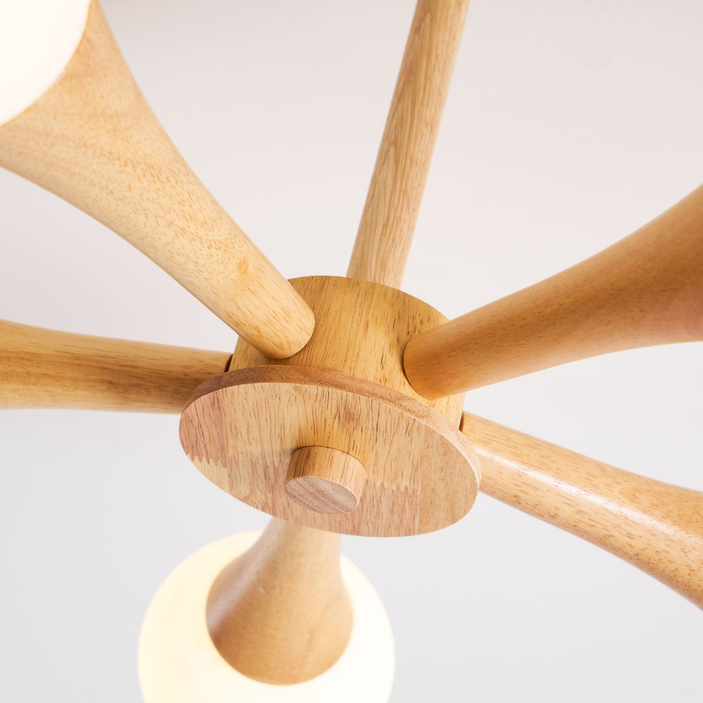Extreme close-up of the wood joinery on this Clérachic chandelier, with one opal glass globe glowing softly at the base of the hub.