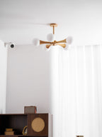 Mounted in a curtained corner with a small wall sensor nearby, this Clérachic chandelier glows above the dark wood cabinet below.