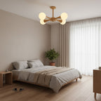Mounted above a bed with grey linens and sheer curtains, this Clérachic chandelier's pale wood arms hold five glowing opal globes.