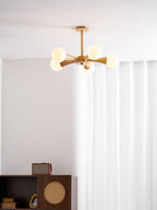 Mounted in the corner of a room with sheer curtains, this Clérachic chandelier glows above a dark wood cabinet holding framed photos.