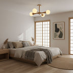 Centred above a bed with grey linens and a shoji-style window, this Clérachic chandelier lights a calm bedroom in pale wood and opal glass.