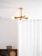 Ceiling-mounted in a curtained corner above a dark wood cabinet, this Clérachic chandelier's pale wood arms glow warmly.