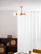In a curtained room corner with a mustard-yellow chair and a record player on a dark wood cabinet, this Clérachic chandelier glows warmly.