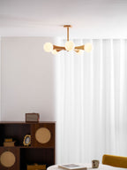 Cropped closer in the same curtained corner, this Clérachic chandelier's pale wood arms glow above the dark wood cabinet.