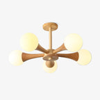 Photographed on a plain grey background, this Clérachic chandelier shows its pale wood arms and five opal glass globes, one lit softly at the centre.