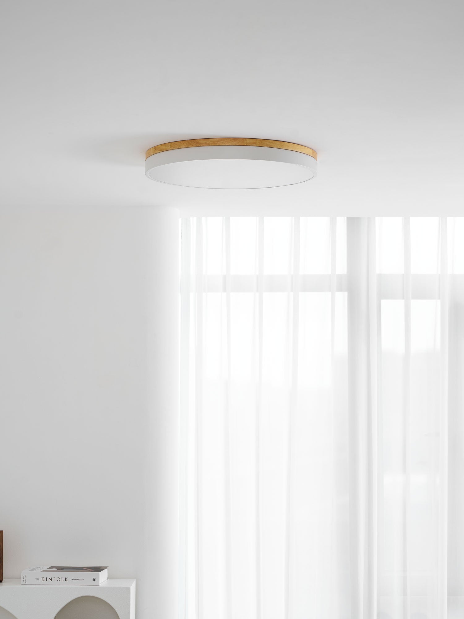 Circular wood ceiling lamp with natural wood tone over a seating area
