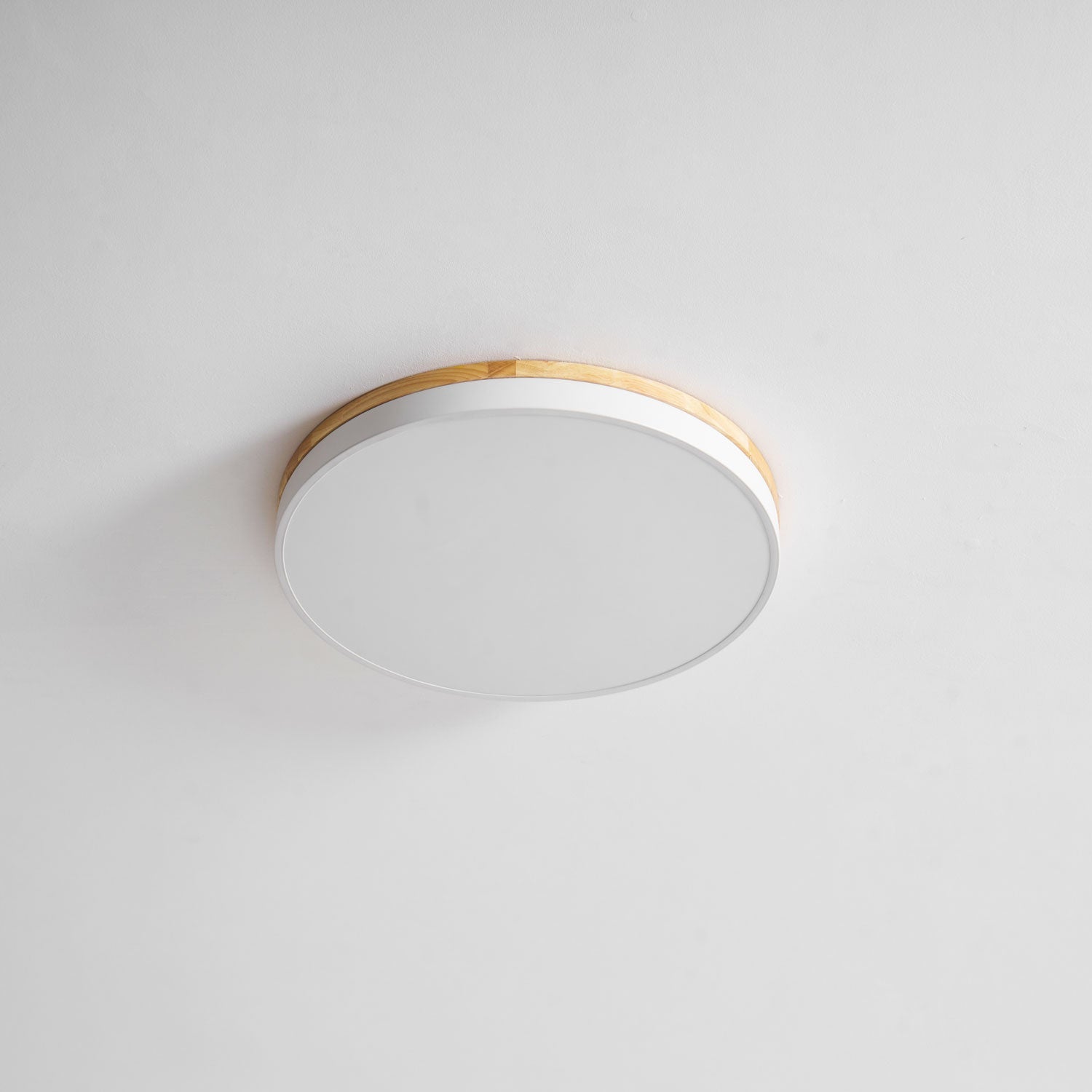 Circular wood ceiling lamp casting soft light over a neutral interior