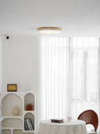 Circular wood ceiling lamp seen at an angle showing the slim depth