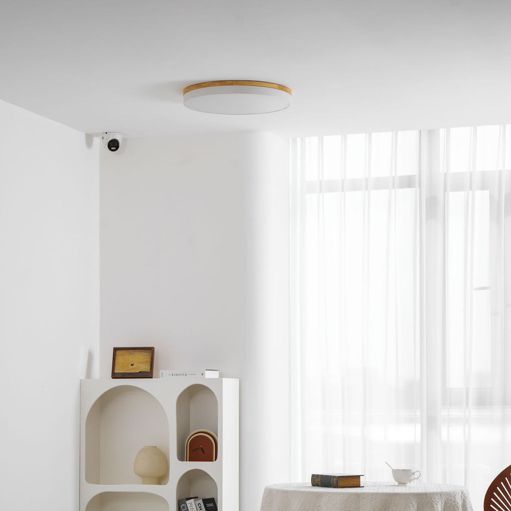 Circular wood ceiling lamp lit in a cosy living room corner