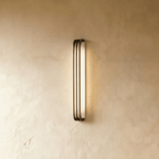 Clérachic marble and copper wall light switched on, the glow running unbroken from the rounded top of the panel to its rounded base.
