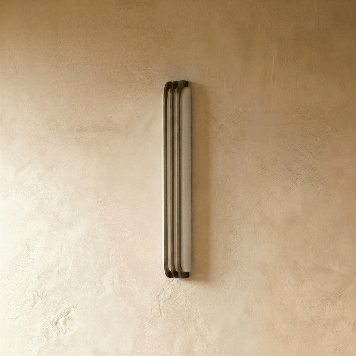 Clérachic marble and copper wall light switched off, showing the pale stone panel with three copper bars standing in front of its face.