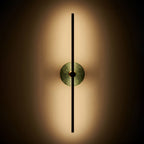 Clérachic wall sconce lit against a dark background, its green stone disc softly backlit by warm light.