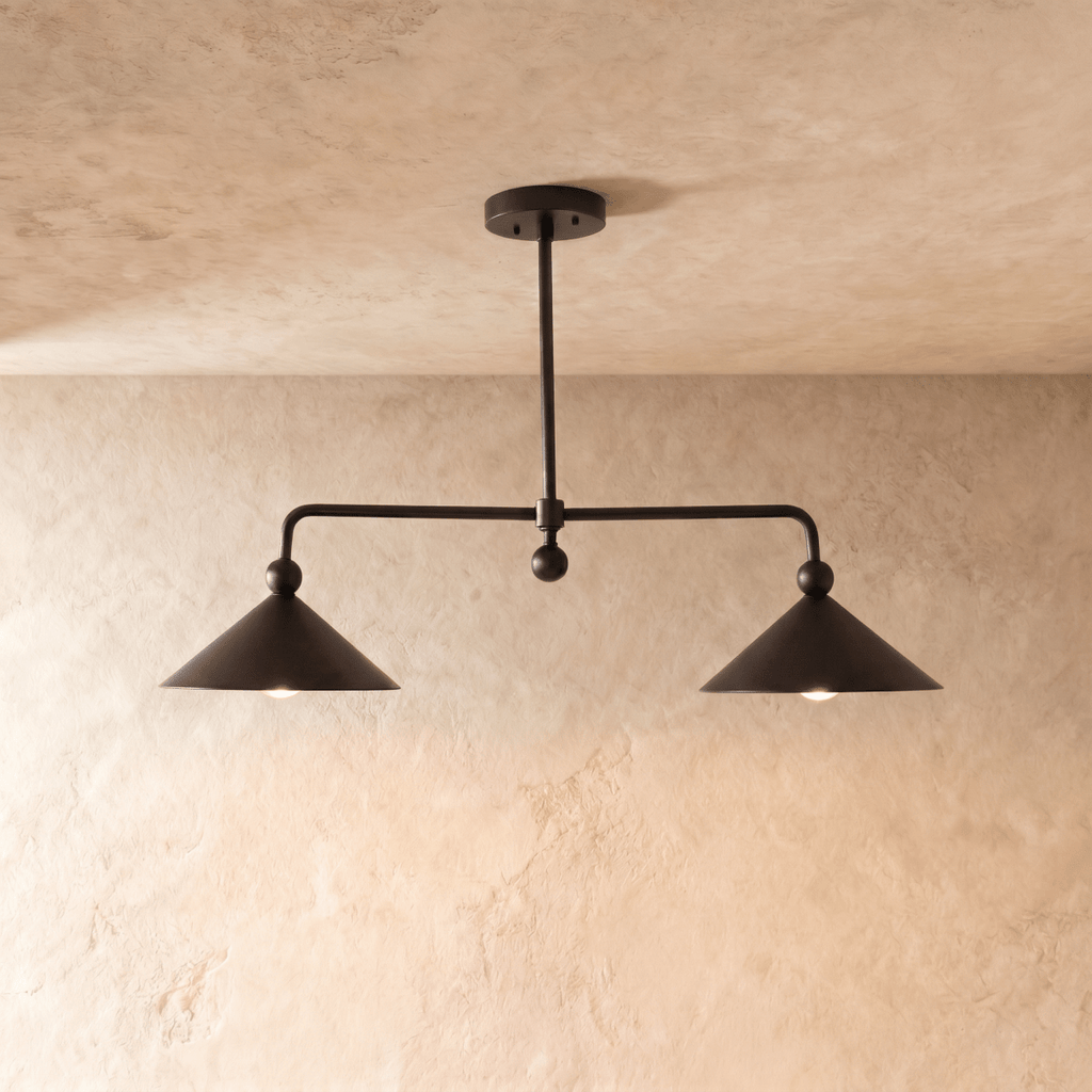 Clérachic chandelier in matte black, two cone shades hung from an angled ceiling bar over plaster.