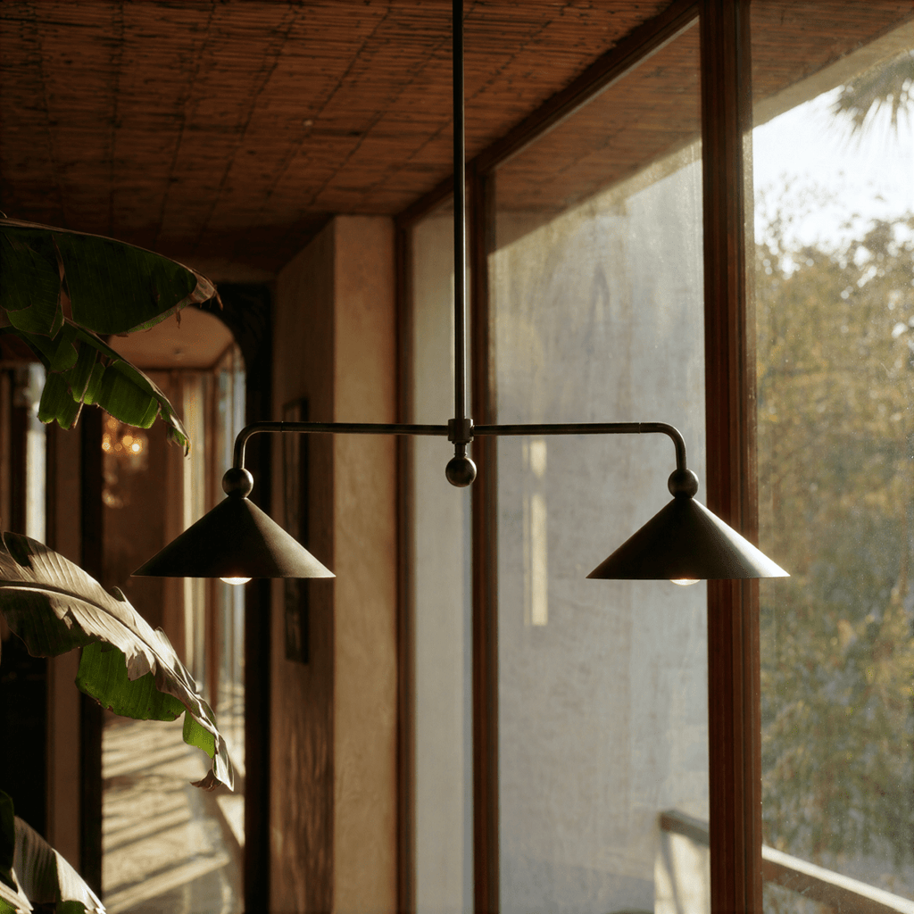 Clérachic chandelier in matte black over a wood dining table on a plant-filled lakeside balcony.