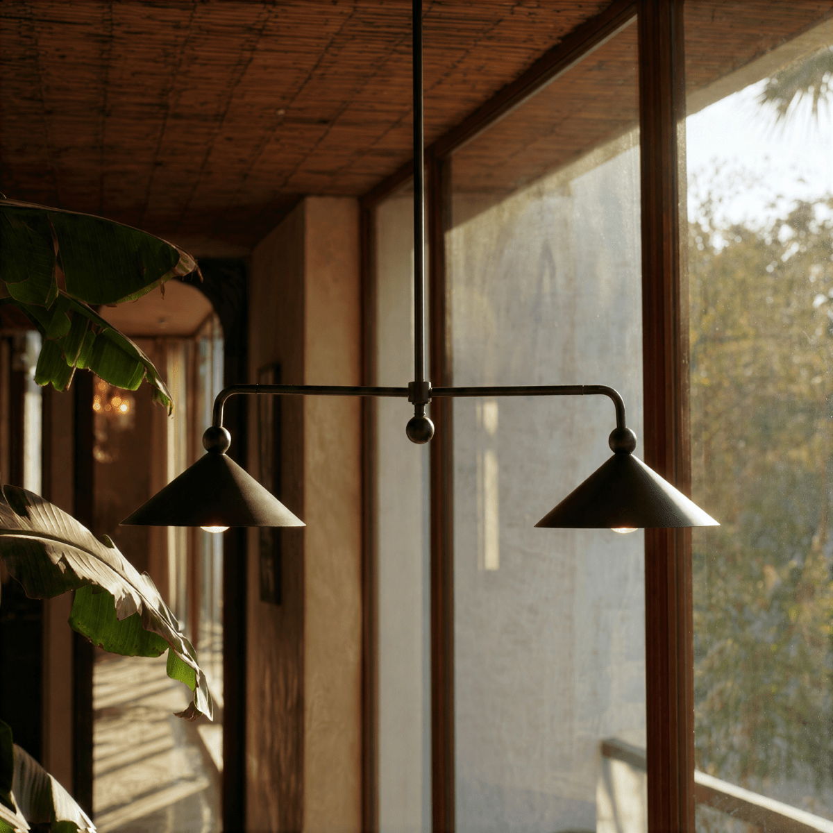 Clérachic chandelier in matte black over a wood dining table on a plant-filled lakeside balcony.