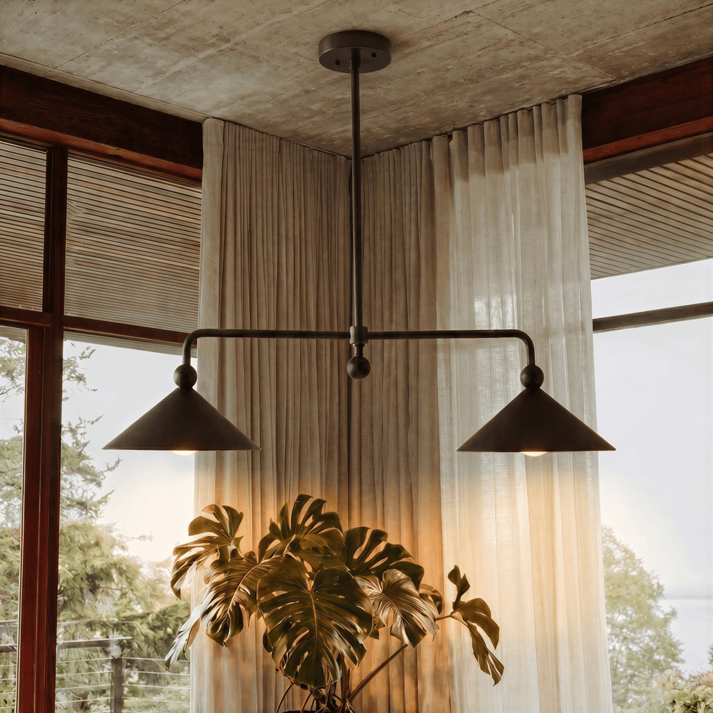 Clérachic chandelier in matte black beside sheer curtains and a large monstera under a concrete ceiling.