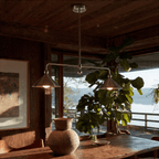 Clérachic chandelier in chrome over a rustic wood table with a potted plant and a lake view beyond.